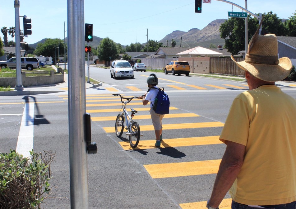 Kid walking bicycle in crosswalk.